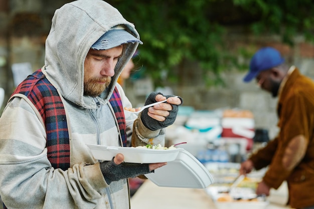チャリティー フードを食べるホームレスの男性
