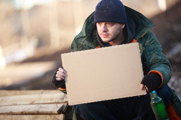 Homeless man holds blank cardboard for your text