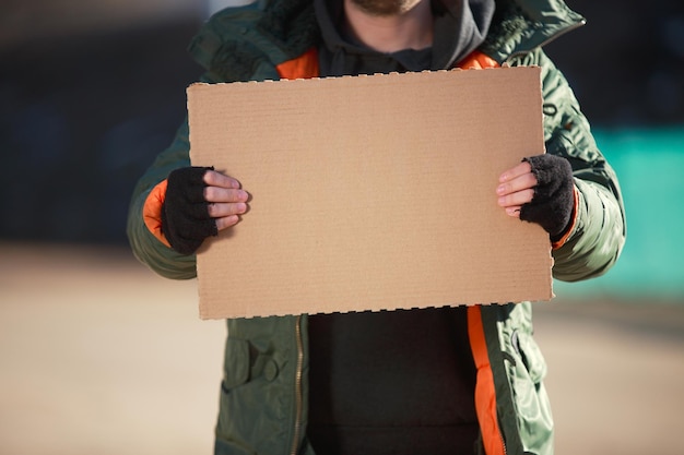 Photo homeless man holds blank cardboard for your text