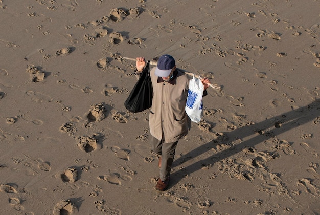 ビーチの砂で物事を探しているホームレスの男性