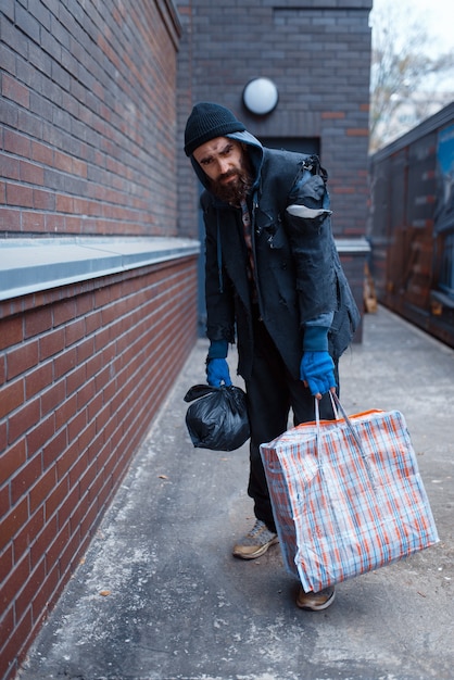 Homeless man with bag on city street.