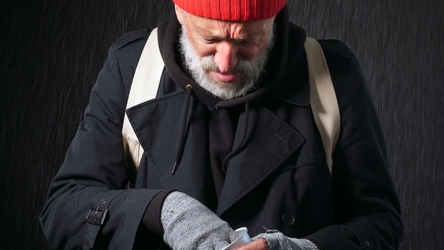 Uomo anziano senza tetto, mendicante, uomo barbuto che conta le monete per mangiare e bere, fondo isolato