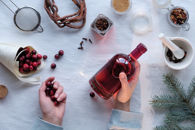 Homemade alcoholic drink prep. Flat lay on cranberry tincture with ethanol, berries and spices.