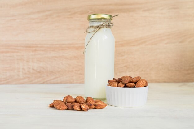 Homemade Almond milk in a bottle and nuts in white porcelain bowl