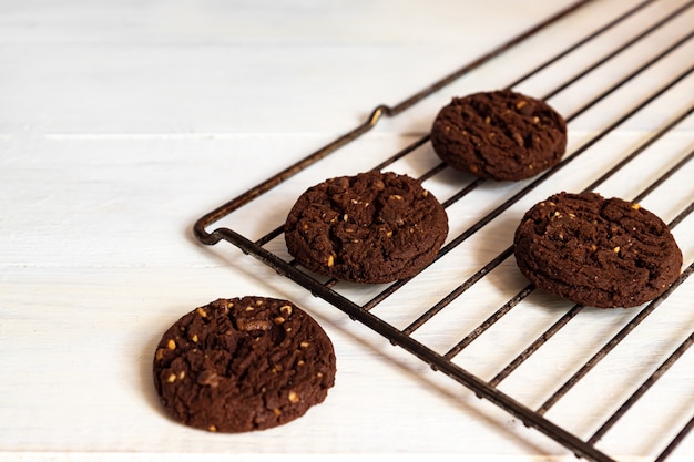 Homemade american chocolate cookies with nuts on a grill on white wooden background. Fresh pastry.