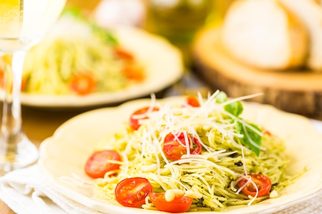 Homemade angel hair pasta with pesto sauce and roasted cherry tomatoes.