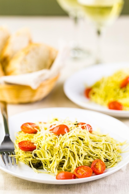 Homemade angel hair pasta with pesto sauce and roasted cherry tomatoes.