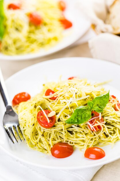 Homemade angel hair pasta with pesto sauce and roasted cherry tomatoes.