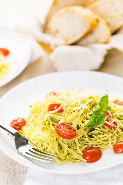 Homemade angel hair pasta with pesto sauce and roasted cherry tomatoes.