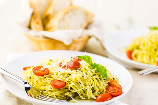 Homemade angel hair pasta with pesto sauce and roasted cherry tomatoes.