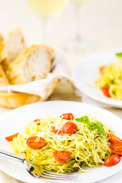 Homemade angel hair pasta with pesto sauce and roasted cherry tomatoes.