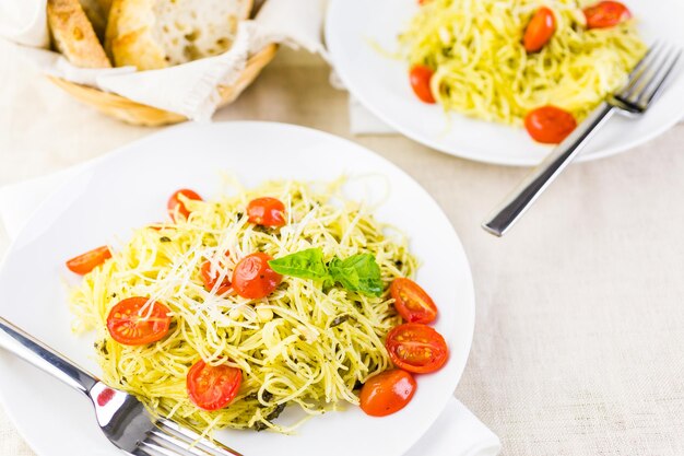 Homemade angel hair pasta with pesto sauce and roasted cherry tomatoes.
