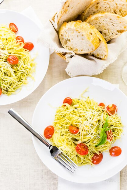 Homemade angel hair pasta with pesto sauce and roasted cherry tomatoes.