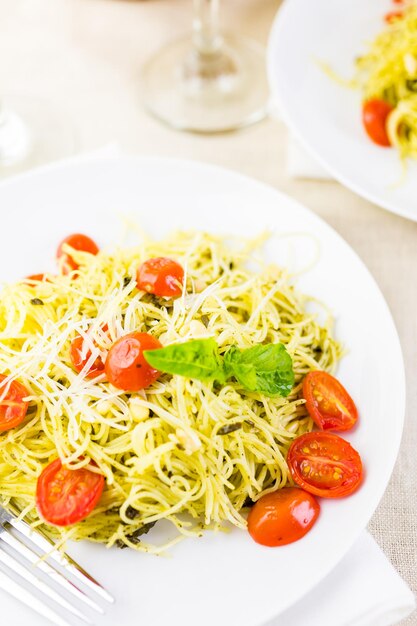 Homemade angel hair pasta with pesto sauce and roasted cherry tomatoes.