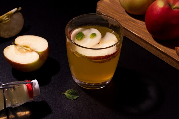 Homemade apple juice in a glass next to fresh apples