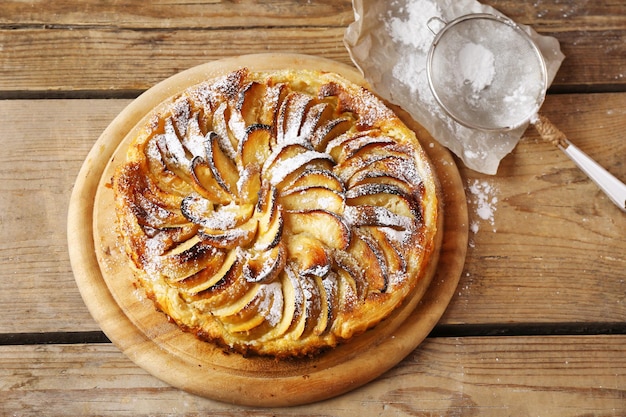 Homemade apple pie on cutting board on wooden background