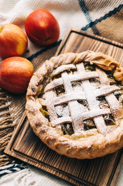 Homemade apple pie on a wooden board with cinnamon and a golden crust. Autumn season