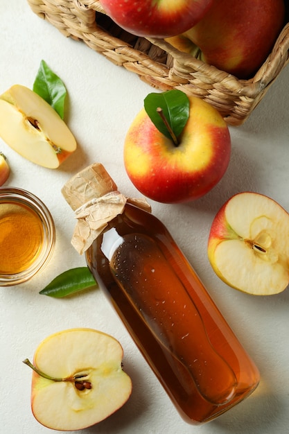 Homemade apple vinegar and ingredients on white table