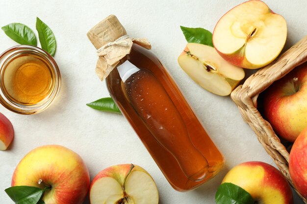 Homemade apple vinegar and ingredients on white table