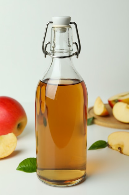 Homemade apple vinegar and ingredients on white table