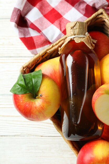 Homemade apple vinegar and ingredients on white wooden table