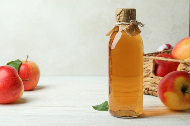 Homemade apple vinegar and ingredients on white wooden table