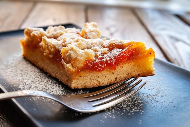Homemade apricot pie A slice of rustic hot sweet cake sprinkled with icing sugar and a fork
