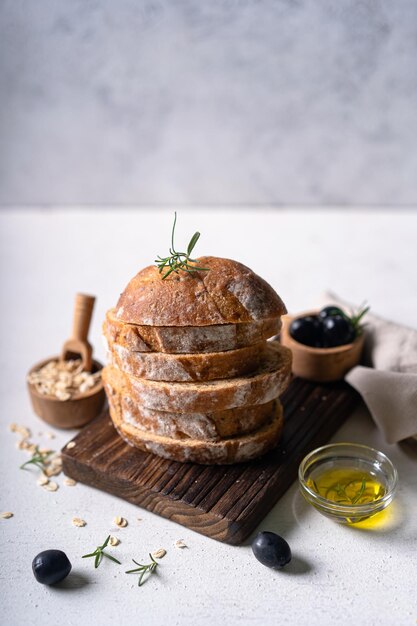 Homemade artisan sourdough ciabatta slice bread with olives and rosemary on a white abstract table