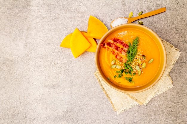 Homemade autumn hot pumpkin cream soup with smoked bacon and seeds