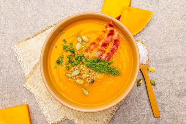 Homemade autumn hot pumpkin cream soup with smoked bacon and seeds