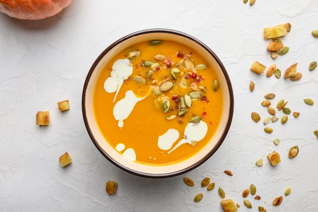 Zuppa di crema di zucca autunnale fatta in casa con semi di crostini di crema e basilico su fondo di legno chiaro