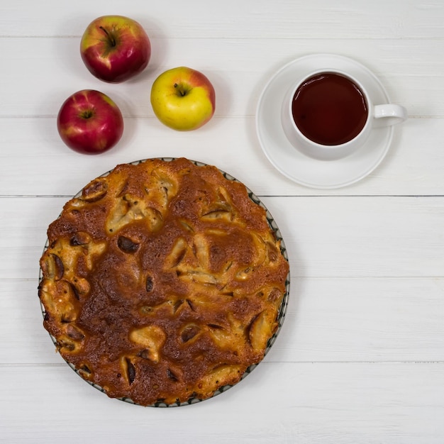 Homemade baked apple pie in a plate on a white wooden table ready to eat Place for an inscription Uneven grungy white background from natural putty White texture background