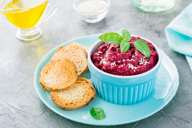 Homemade baked beetroot hummus in a bowl with sesame seeds