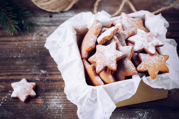 Homemade baked Christmas gingerbread cookies with icing sugar in the box on wooden background