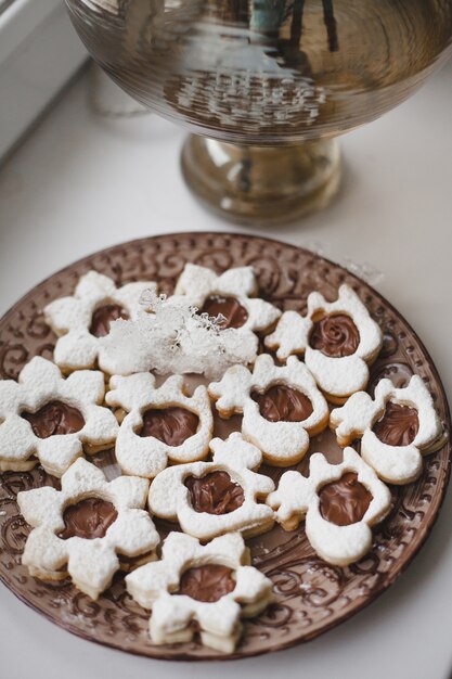 집에서 맛있는 검역을 요리하려면 흰색 창턱에 접시에 초콜릿으로 만든 구운 쿠키