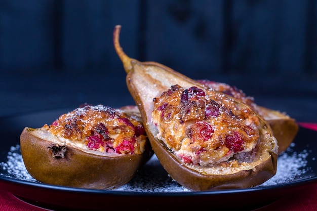 Homemade baked pears with honey red cranberries and walnuts in black plate on wooden background healthy food close up