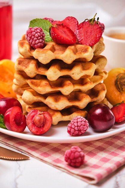 Homemade baked traditional Belgium waffles with berry fruits and cup of coffee, selective focus