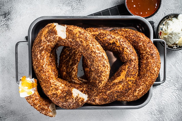 Homemade baked Turkish simit or Gevrek bagel with kaymak and honey. Gray background. Top view.