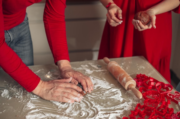 Concetto di cottura fatto in casa mani di uomo e donna irriconoscibili che cucinano biscotti che cuociono a casa clo rosso