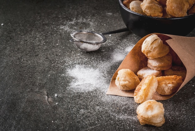 Homemade baking, puff pastries. Trendy food. Cronuts popcorn, puff donuts holes, in a black bowl and a paper bag