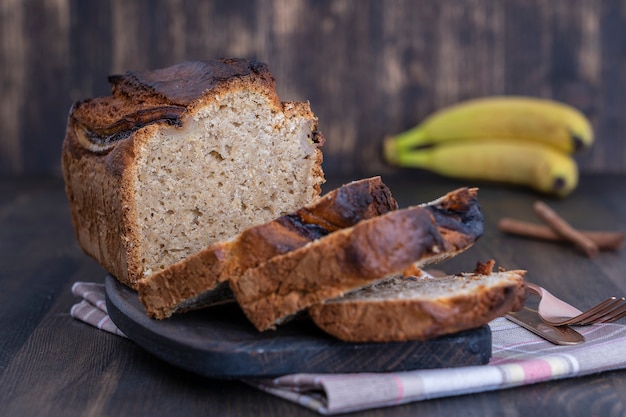 Homemade banana bread with cinnamon on a wooden background, close u. Banana bread loaf, fresh baked from oven on wood table background, vintage rustic still life style. Concept of bakery
