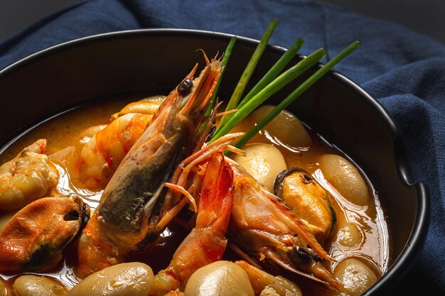 Homemade bean stew with prawns and mussels on dark background. Typical Spanish food