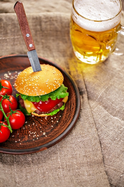 Homemade beef burger and fresh vegetables on Clay dish with glas