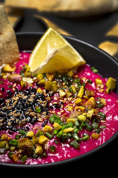 Homemade Beet and Chickpea Hummus with Vegetable CruditÃÂ©s and Unleavened Bread on Dark Background