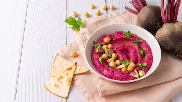 Homemade Beetroot hummus on white table copy space