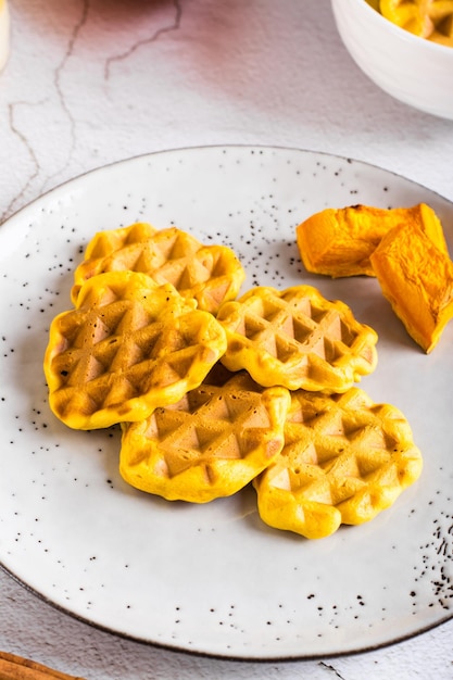 Homemade belgian pumpkin waffles on a plate on the table Autumn baking Closeup vertical view