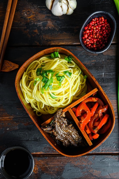 Homemade Bento pack lunch grilled beef and noodles with ingredients top view ower rustic wood dark background