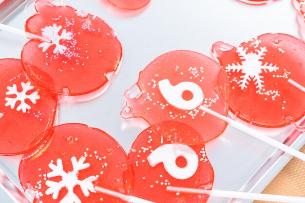 Homemade berry flavor lollipops with snowflakes on a white lollipop sticks.