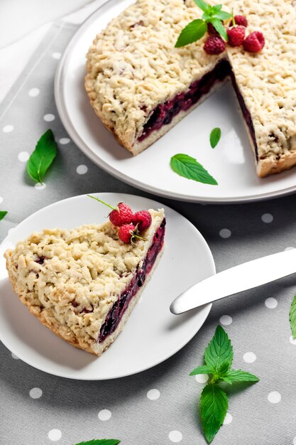 Homemade berry shortcrust pie with crumble on plate and grey dotted cloth