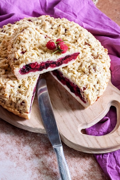 Foto torta di pasta frolla fatta in casa ai frutti di bosco con crumble su tavola di legno e panno viola